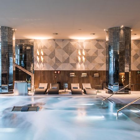 Grand Hyatt Barcelona Hotel Exterior foto The photo shows a sophisticated spa area featuring a large, inviting pool with a calm, relaxing atmosphere. The pool area is surrounded by elegant columns and has a modern design. There are comfortable lounge chairs positioned nearby, and the lightin